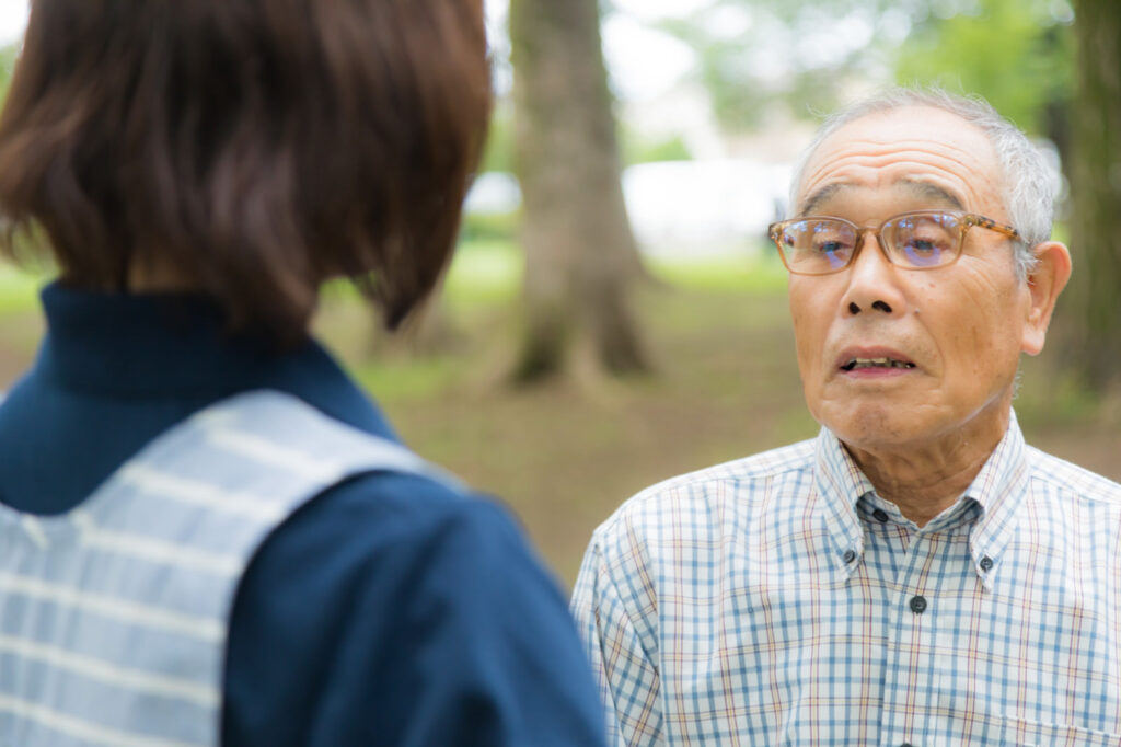 介護現場で介護士と話す高齢の男性