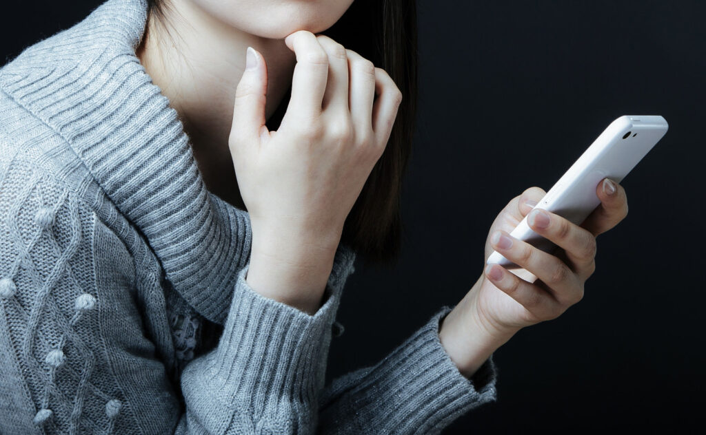 スマホを見て不安を感じる女性